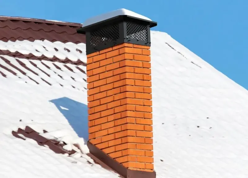 Brick chimney with a protective chimney cap and visible exterior masonry.